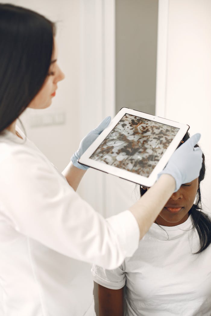 Healthcare professional examining patient's skin using tablet for detailed analysis.